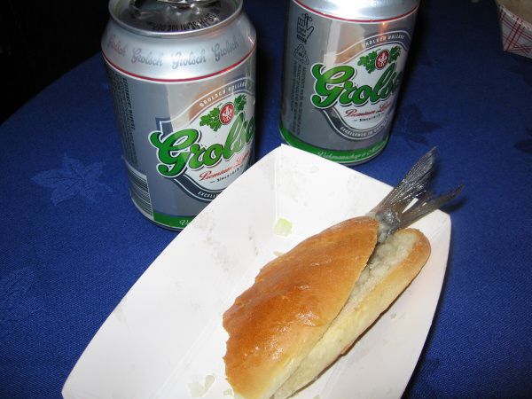 A herring on a sandwich with onions, and Grolsch beer.